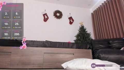 Media: Video of a modern living room with a black leather sofa, a wooden coffee table, and a Christmas tree adorned with red ornaments and a star on top.