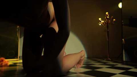 Media: A video depicting a woman in a black dress kneeling on a black-and-white checkered floor, with a man's legs visible, in a dimly lit room with a chandelier.