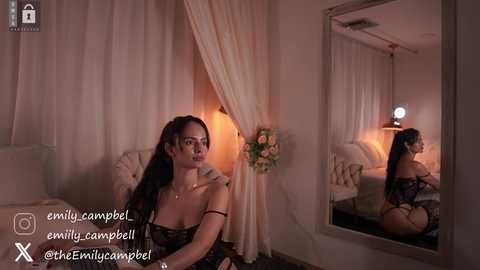 Media: A video of a brunette woman in lingerie kneeling on a bed, gazing at her reflection in a mirror, in a dimly lit, romantic bedroom setting.