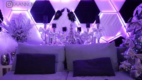 Media: Video of a luxurious, modern living room with hexagonal white walls lit by purple LED lights, featuring a grey sofa, white Christmas tree, and decorative silver boxes.