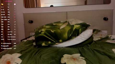 Media: A video shows a bed with a green floral duvet and pillows. The room has a white wall and a large mirror reflecting part of the room. Social media icons are present on the left side.