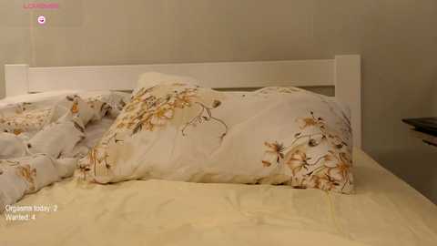 A video of a neatly made bed with a white headboard and a cream-colored duvet cover featuring floral designs. The bedding appears fresh and well-organized.