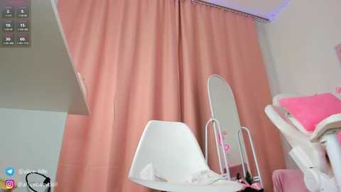 Media: Video of a hospital room with peach curtains, a white bed with pink pillow, a mirror, and a metal pole, showing a clean and modern medical setting.