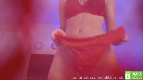 Media: A video of a woman in red lingerie, holding a red towel, standing in a dimly lit room with purple lighting.