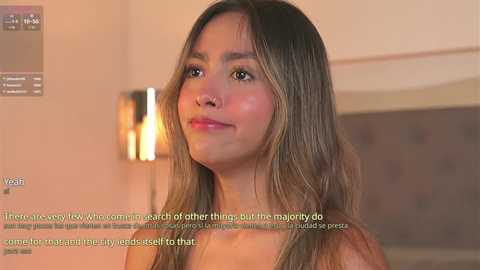 Media: Video of a young Asian woman with long, straight, light brown hair, fair skin, and a serene expression. She is topless, standing indoors against a blurred, beige background. Text overlays her face, discussing her lack of interest in majorities.