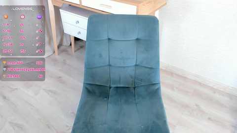 Media: Video of a teal, tufted armchair with a light wood floor and a white wall background. A virtual reality headset and controller are placed on a white dresser in the background.