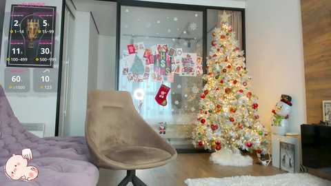 Media: Video of a modern living room with a beige, curved armchair, a festive, decorated Christmas tree, and a wall-mounted TV displaying a sports score.