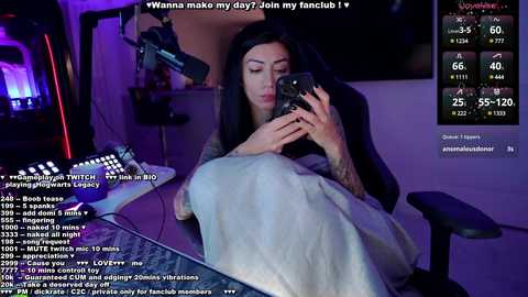 Media: A video captures a tattooed woman with long black hair, sitting in a dimly lit room with a computer monitor showing fan club activity.