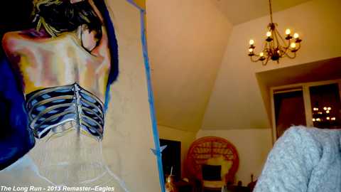 Media: Video of a brightly lit, modern living room with a large, colorful painting of a woman in a corset on the left, a chandelier above, and a round \"The Lone Ranger\" poster on the right.