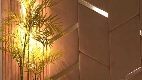 Media: A video captures a bamboo plant with lush green leaves bathed in warm, golden light, juxtaposed against a modern, geometrically patterned wall with metallic accents. The scene exudes a serene, minimalist aesthetic.