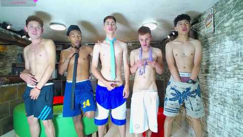 Media: Video of five shirtless, young, athletic men in various sports attire, posing in a colorful, tiled indoor setting.