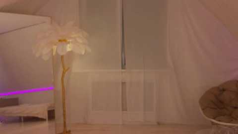 Media: Video of a cozy attic room with a white, flowery lamp, white sheer curtains, and a plush chair, illuminated by soft purple light.