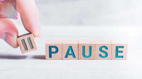 Media: A close-up video shows a hand assembling a wooden block puzzle with the word \"PAUSE\" in blue letters. The background is a light, blurred surface.