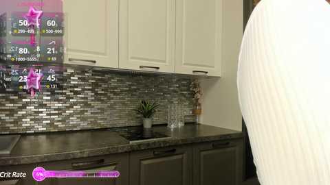 Media: Video of a modern kitchen with a man wearing a white sweater facing a black countertop, featuring a digital fitness app overlay displaying his progress and stats.