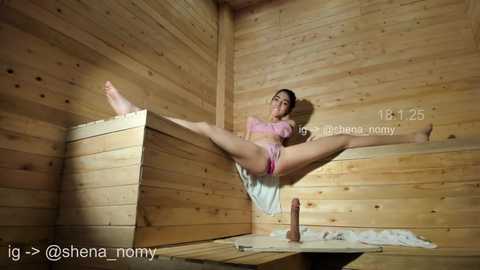 Media: Video of a nude woman with dark hair, sitting on a wooden bench in a sauna, legs spread wide, wearing a pink bikini.