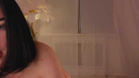 Media: A video shows a close-up of a woman's bare back with a white lily in her hair, and a blurred bathroom with a shower curtain in the background.