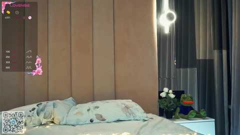 Media: Video of a modern bedroom with light wood-paneled walls, a bed with white floral sheets, a bedside table with a lamp, potted plants, and a QR code overlay.