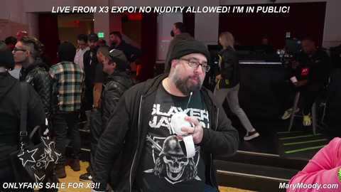 Media: Video of a bearded man in glasses wearing a black hoodie, standing in a crowded convention hall. Text overlays read, \"Live from 3 Expo! No nudity allowed! I'm in public!\