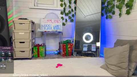 Media: Video of a cozy, festive room with white walls, green plants, a white table, presents, a \"Merry Links\" sign, and a circular light ring.