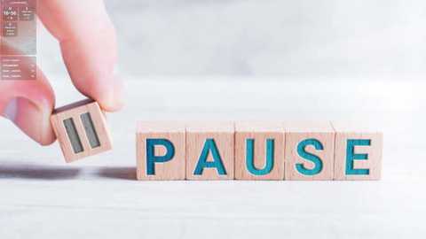 Media: Video of a hand holding a wooden letter \"P\" with the word \"PAUSE\" in wooden blocks. The background is a blurred, light-colored wooden surface.