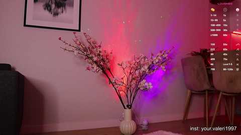 Media: A video of a modern living room with pink and purple LED lights illuminating a floral arrangement in a white ceramic vase on a wooden floor.