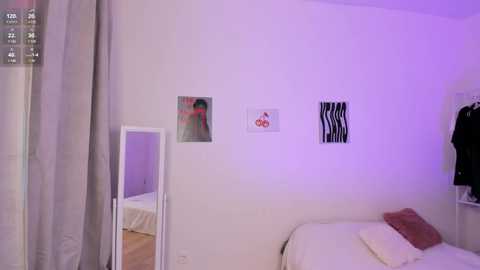 A video of a minimalist, white-walled bedroom with a mirror, a bed, a hanging coat, and two abstract art pieces. The room is softly lit with purple lighting, creating a serene ambiance.