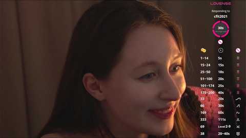 Video of a smiling, fair-skinned woman with long, straight brown hair, wearing a red jacket, set against a dimly lit background. Social media app interface overlay displays her heart rate and other metrics.