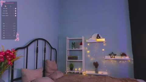 Media: Video of a cozy bedroom with pastel blue walls, a black metal bed frame, white shelves adorned with fairy lights, a pink flower arrangement, and a white wall calendar.