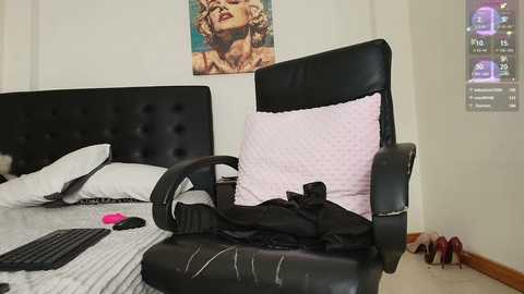 Media: Video of a modern bedroom with a black leather gaming chair, white bed, pink pillow, and a Marilyn Monroe poster.