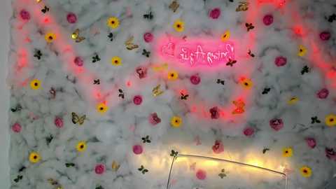 Media: A vibrant video of a white marble wall adorned with colorful flower decals and a glowing pink neon sign reading \"Stay Strong\" in the center.