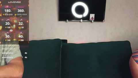 Media: Video of a person wearing a gray shirt, sitting on a dark green couch with a black wall-mounted ring light. Weather app overlay shows 180\u00b0, 30\u00b0, and 40\u00b0 temperatures.