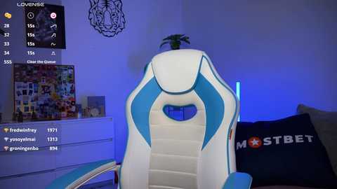 Video of a modern gaming chair with blue and white accents, set against a wall adorned with a tiger head design, in a dimly lit room.