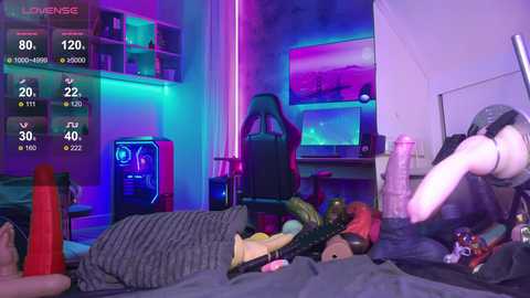 Video of a gamer's messy bedroom, featuring a pink, furry character, an orange dildo, and a cluttered desk with gaming monitors and controllers.