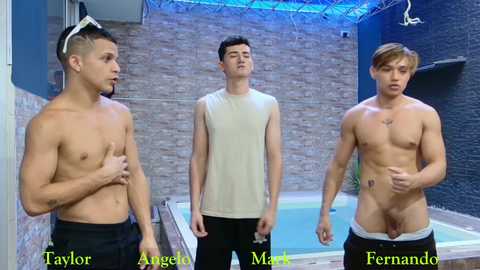 Video of three shirtless men, two in black shorts, one in white, standing near a hot tub in a dimly lit room with blue lighting.