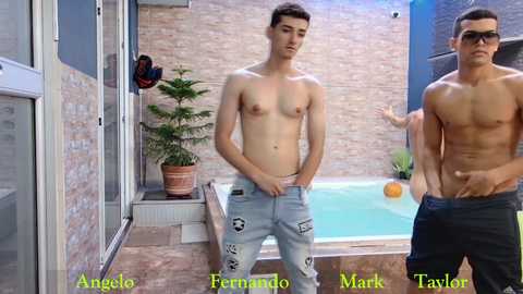 Video of two shirtless young men in a modern outdoor setting, one with a small tattoo, wearing light jeans, standing near a pool.