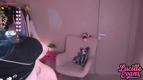 Media: Video of a pink room with a white chair adorned with a panda pillow. A person in black clothes is partially visible on the left.