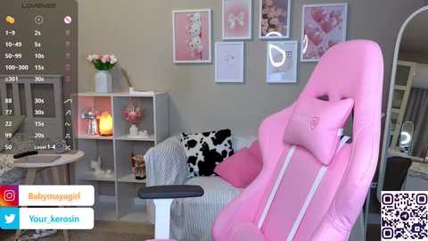 Video of a cozy, pastel-themed living room with pink gaming chair, black and white cow print cushion, white couch, floral wall art, and a digital screen showing social media icons.