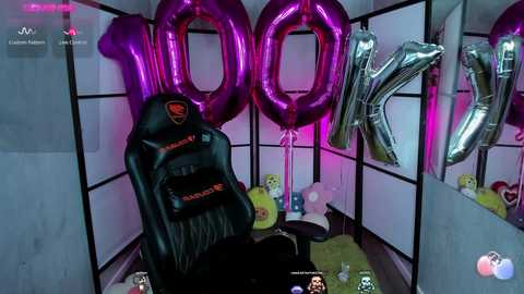 Video of a gamer room with a black gaming chair, two large purple \"1000\" balloons, and \"1000K\" letters, featuring a pink and purple theme, surrounded by stuffed animals and gaming accessories.