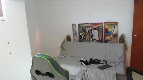 Media: A video of a minimalist bedroom with a white sofa, a green gaming chair, a wooden door, and abstract art on the wall.