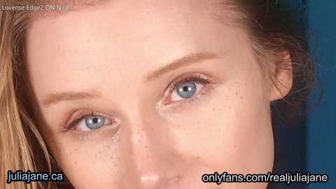 Media: Close-up video of a young woman with fair skin, light brown hair, and striking blue eyes, set against a blue background. The image includes text overlays for OnlyFans and JuliaJane.ca.