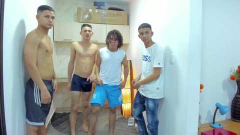 Media: Video of four shirtless Asian men in a small, brightly lit room with white walls and wooden cabinets, wearing only shorts, one holding a yellow lamp.