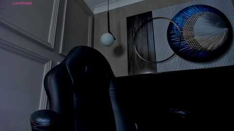 Media: Video of a modern office interior featuring a black leather chair, striped wall, and abstract art with geometric patterns, illuminated by a hanging lamp.