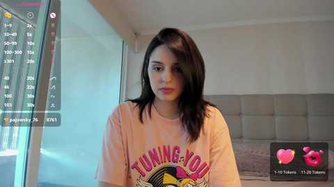 Media: Video of a young woman with long black hair, wearing a pink T-shirt with \"Turning 30\" graphic, in a modern bedroom with a grey headboard.