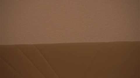 Media: A video depicts a barren, sandy landscape with a smooth, beige-colored horizon and a slightly darker brown foreground, devoid of any visible structures or life. The image conveys a sense of emptiness and isolation.