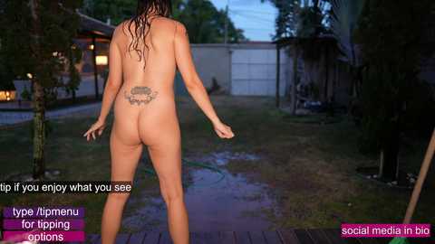 Media: Video of a nude woman with wet hair, visible tattoo, standing in a suburban backyard with a pool, a white garage, and a bicycle.