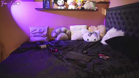 Media: Video of a cozy bedroom with plush toys, including a tiger, on a dark bed, a TV remote, and a black keyboard on the bedspread.