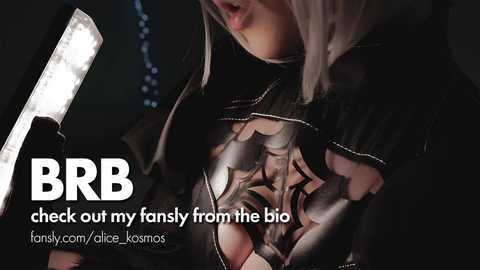 Media: A close-up video of a person in a dark, intricate, metallic bodysuit with a large, stylized mask over their face. The text \"BBR\" and \"fanly.com/dice-komos\" are overlaid.