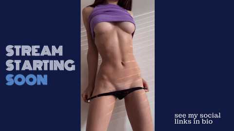 Media: Video of a slender, light-skinned woman with small breasts, wearing a purple crop top and black thong, standing against a dark blue backdrop. Text reads \"STREAM STARTING SOON\" in bold white letters.