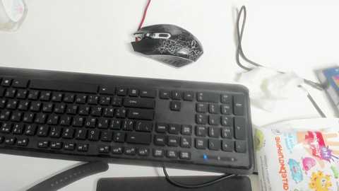 Media: A video of a black computer keyboard with white keys, placed on a white desk. A black mouse with a red cord is on the left, and a colorful cereal box is on the right.