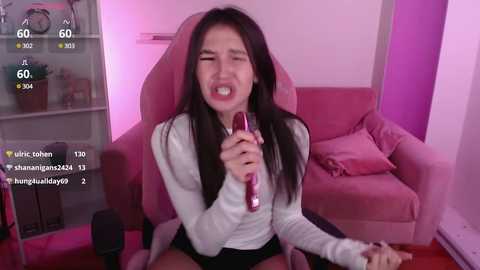 Media: Video of an Asian woman with long black hair, crying and holding a microphone, seated in a pink gaming chair.